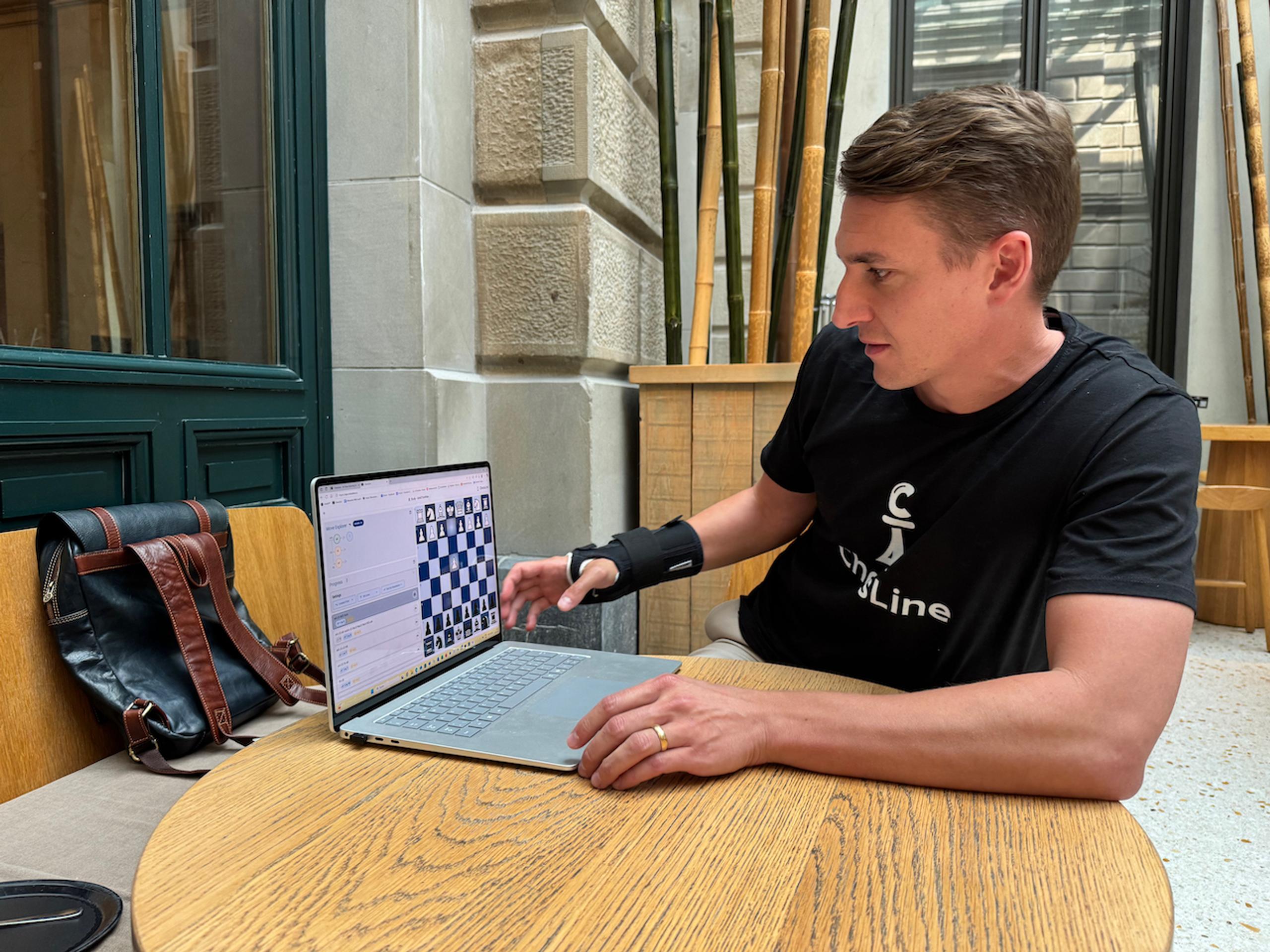 ChessLine CEO Stefan Rau working on laptop with chess application, featured in Swiss Chess Federation interview about learning chess with AI